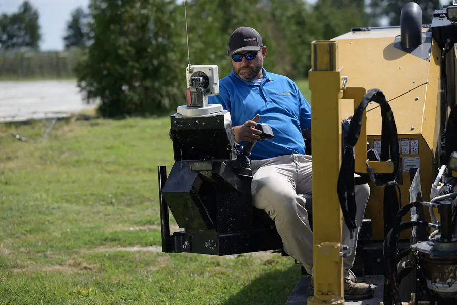 Crew member checking equipment controls beside a drilling rig on a utility job